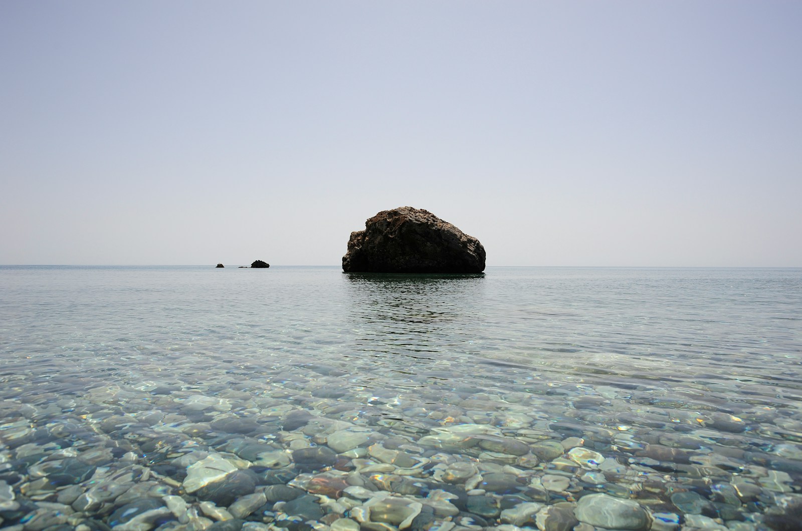 black rock formation in the middle of sea